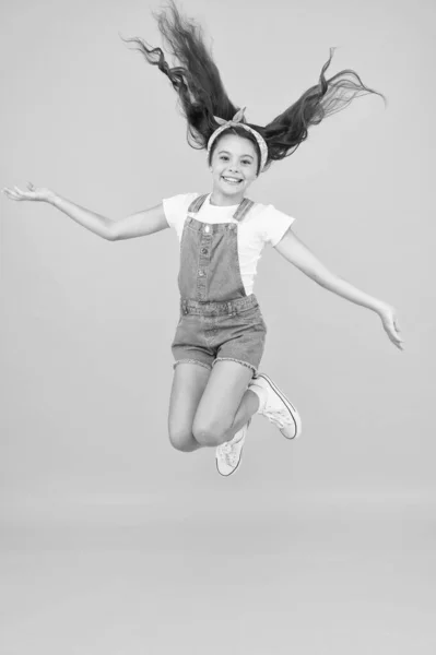 エネルギーに満ちていますアクティブガールは自由を感じる。楽しさとリラックス。気軽に夏休みの気楽な子供だ楽しい時間だ空中のレトロな美しさ幸福のジャンプ。小さな女の子ジャンプ黄色の背景 — ストック写真