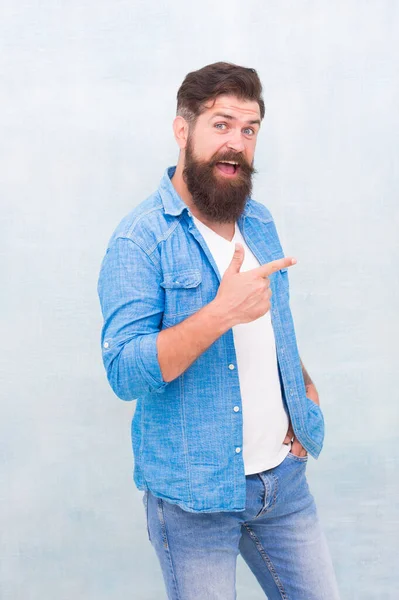 Check it out. Promoting goods. Handsome man with beard pointing index finger. Promotion concept. Direction and recommendations. Shopping promotion. Items for men. Good looking guy. Cheerful hipster — Stock Photo, Image