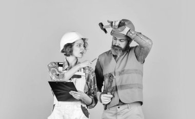 Yuvanın yenilenmesi. Yenileme konsepti. Çift planlama yenileme dairesini değiştirir. Belgelere bakan bir çift. Kadın ve erkek güvenlik kaskı takıyor. Tadilat için aile hesapları