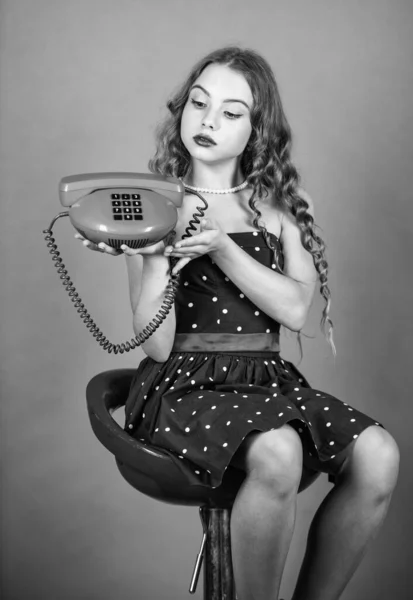 Kendine güvenen bir güzellik. Mutlu kız sohbeti. Çocuk sandalyenin tuşlu telefonuna oturuyor. İletişim konsepti. Eski tarz. İnternetten alışveriş. Retro kız telefonda konuşuyor. Güzel çocuk eski telefonlardan konuşuyor. — Stok fotoğraf