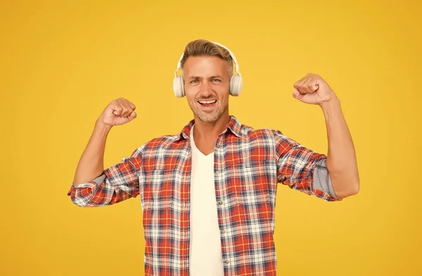 Happy man flex δυνατά χέρια ακούγοντας μουσική σε μοντέρνα ακουστικά κίτρινο φόντο, ηχητική ισχύς — Φωτογραφία Αρχείου