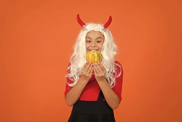 Boldog lány Halloweenkor viselni vicces karnevál jelmez és ördög szarvak beltéri gazdaság tök, halloween magic — Stock Fotó