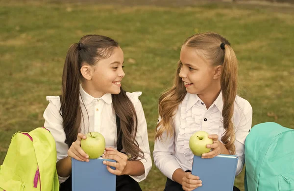 Nossos cérebros precisam ser alimentados com lanche vitamínico. Meninas felizes comem maçãs na grama verde. Um lanche da escola. Pausa para lanches. Alimentação saudável e lanches. Comida vegetariana. Dieta e dieta. Pequeno-almoço ou almoço — Fotografia de Stock