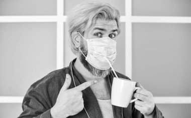 Hijyen konusunda ciddiymiş. Ağız ve burnu maskeyle örtün ve maske ile yüz arasında boşluk olmadığından emin olun. Tamamen korunuyor. Koronavirüsten korumak için maske takıyor. Maskeli adam saman kullanarak çay içer.