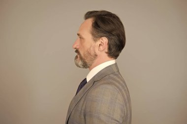 Yakışıklı, olgun, sakallı, takım elbiseli bir adam.