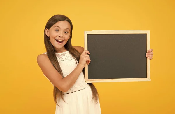 Boas notícias para ti. Chalkboard para informação. Quadro negro em branco. Algo que precisas de saber. Menina sorridente feliz segurar quadro negro. Criança pequena com quadro negro em branco. Propaganda espaço de cópia promoção — Fotografia de Stock