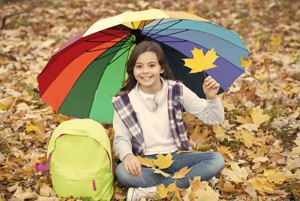 Felice adolescente bambino godere di foresta autunnale con bella natura stagionale sotto colorato ombrello tenere foglie d'acero a borsa della scuola, previsioni del tempo — Foto Stock