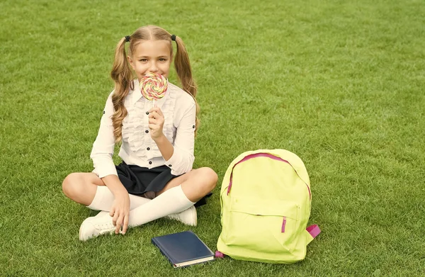 Bilgi günü. Modern okul eğitimi. Mutlu çocukluk. Kitaplı genç kız. Küçük tatlı kız tatlı lolipop yiyor. Çocuklar için edebiyat eğitimi. belge dizini ile öğren — Stok fotoğraf