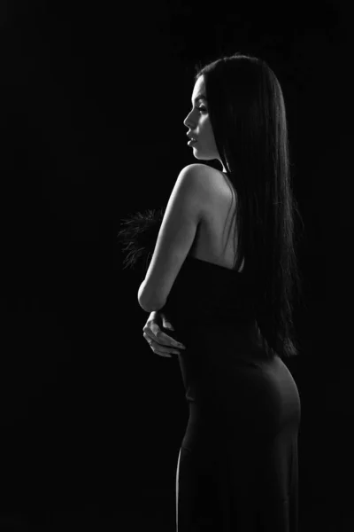 Jovem mulher bonita usar vestido de noite preto. menina com ombros nus posando sobre fundo preto. Retrato de jovem mulher elegante em vestido elegante preto. cuidados com a pele e maquiagem. vestido preto agradável — Fotografia de Stock