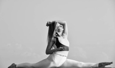 Kadın ikiye bölünmüş olarak oturuyor. Spor giyim sektöründe esnek bir kız. Yoga yapan genç ve çekici bir kadın. Ayrılma egzersizi. Bacak kasları jimnastik için egzersiz yapıyor. Seksi, fit vücutlu güzel bir kadın.