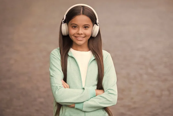 Criança alegre usar fones de ouvido com música música ao ar livre apreciando melodia, de volta à escola — Fotografia de Stock