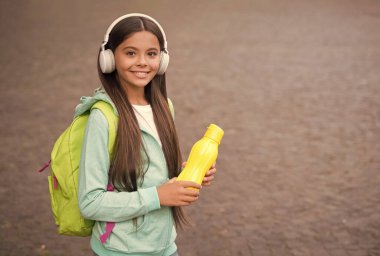 En sevdiği şarkıyla kulaklık takan neşeli genç kız spor yaptıktan sonra susar. Ve su şişesi, günlük su.