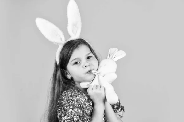 Infância feliz. bonito criança jogar com brinquedo. conceito de loja de brinquedos. menina em orelhas de coelho engraçado. Feliz feriado de Páscoa. preparação de férias de primavera. Um coelhinho da Páscoa. menina pequena segurar lebre brinquedo amarelo fundo — Fotografia de Stock