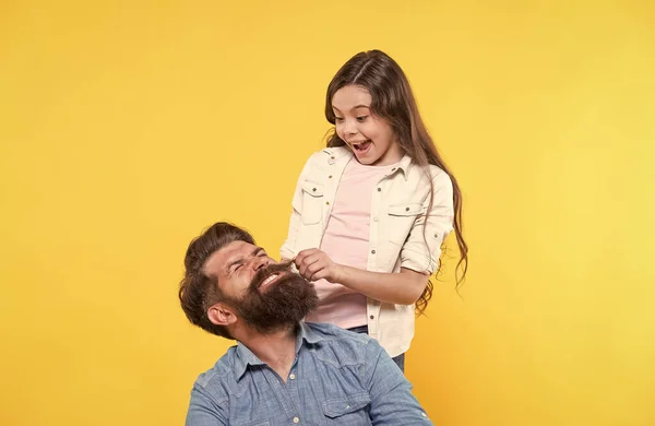 Мой отец хипстер. Маленькая девочка дергает хипстерскую бороду. Счастливая семья на желтом фоне. Парикмахерская хипстеров. Парикмахерская. Парикмахерская. Кустистая борода великолепна. — стоковое фото