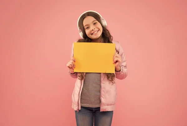 Feliz adolescente escuchar música en los auriculares que presentan papel vacío, la educación escolar —  Fotos de Stock