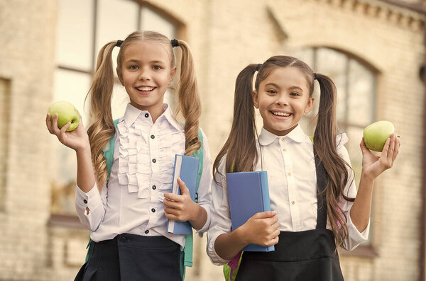 Учащиеся одноклассницы с рюкзаками, имеющие школьный обед, концепция витаминного питания