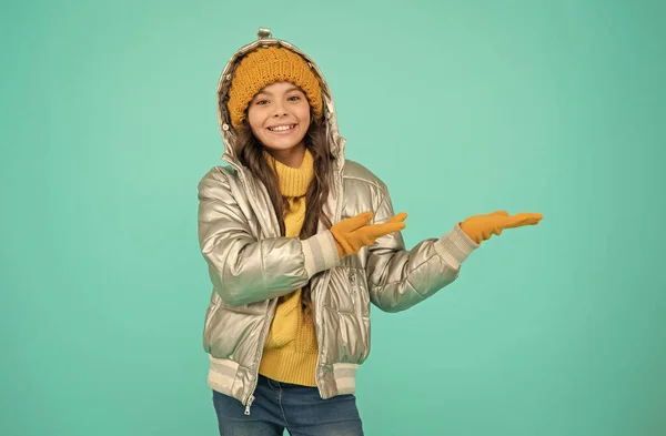 Menina adolescente sorridente em casaco acolchoado ou puffer pronto para passar férias de inverno e férias no conforto e calor apresentando produto, espaço de cópia, estância de esqui — Fotografia de Stock