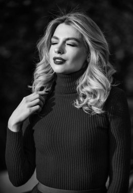 Sevimli kız geçen güneş ışınlarının tadını çıkarıyor. Şık kıyafetler. Kadınlık ve şefkat. Sonbahar tarzı kıyafetler. Sonbahar modası. Sonbahar parkında yürüyen bir kadın. Samimi örgü giysiler. Örgü süveter