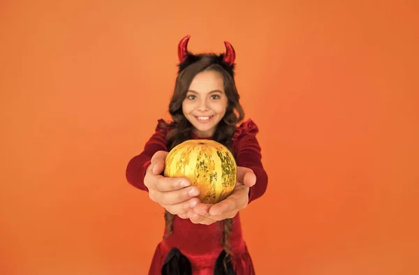 Pumpkin vegetable in hands of happy devil kid wear horns costume of imp on halloween party, selective focus, halloween food — Stock Photo, Image