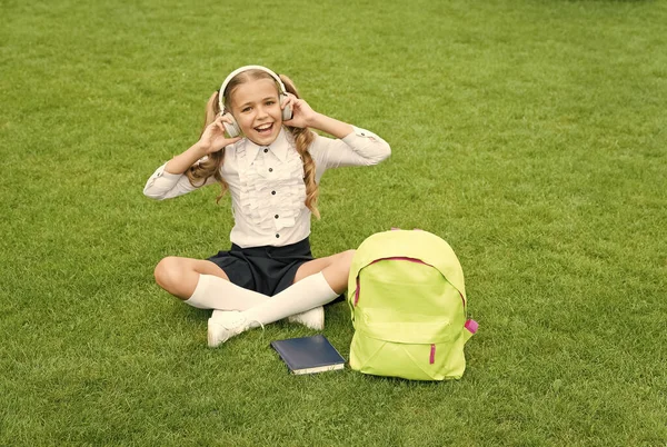 Eğitim en iyi dosttur. Eğitim konsepti. Online öğrenmenin sıradan bir günü. Kızım müzik dinle. Okul bahçesinde kitabı olan mutlu anaokulu kızı. Okula dönüyorum. Çalışkan çocuk kulaklık takıyor