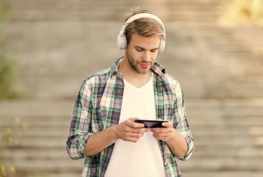 Meşgul adam kablosuz kulaklık kullanıyor, akıllı telefon kullanıyor, oyun konsepti oynuyor