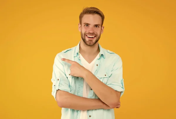Positivo feliz chico señalando dedo y desgaste denim traje de estilo sobre fondo amarillo, presentando producto — Foto de Stock