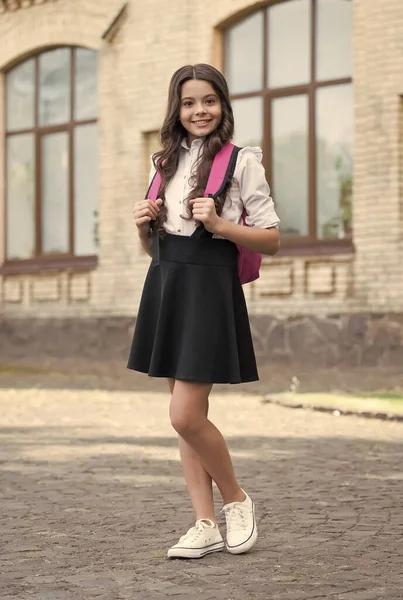 Happy kid in uniform back to school carrying backpack in schoolyard, schooling — Stock Photo, Image