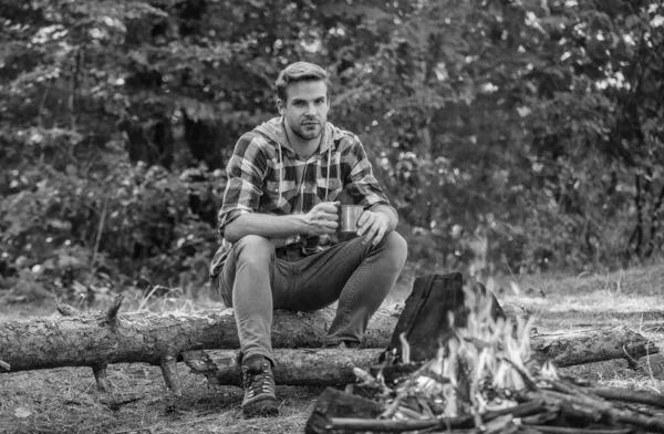 Hombre relajándose en el parque. aventura de senderismo. picnic en el campamento turístico. tomar café en la fogata de picnic. calentarse cerca del fuego. guardabosques en actividades al aire libre. senderismo y camping. pasar un fin de semana de picnic en la naturaleza — Foto de Stock