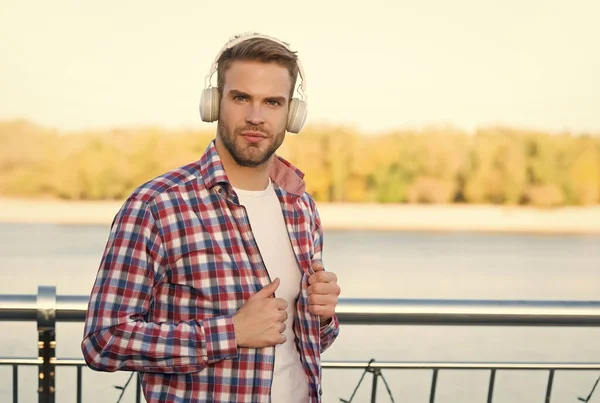 bearded man listen music in digital earphones wearing checkered shirt outdoor, copy space, casual style