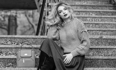 Sonbahar moda trendi. Kız eteğinin üstüne daha büyük bir katman örülmüş. Giyilebilir trendler. Sonbahar formülü. Sonbahar için Süveter ve Etek Kombo stili. Muhteşem saç stili olan kadın merdivenlerde dışarıda oturuyor.