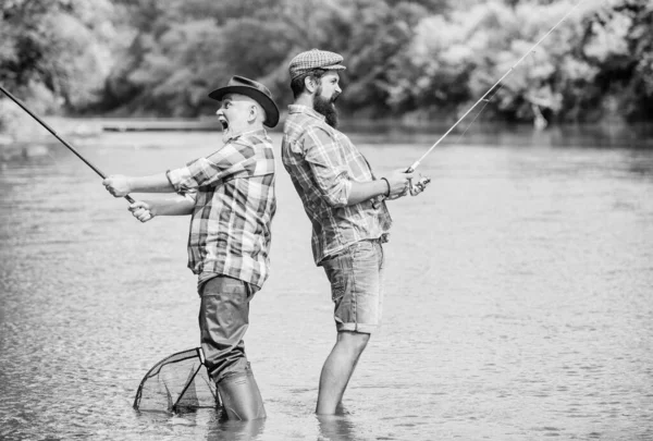 Feliz amistad. pasatiempo y actividad deportiva. Cebo para truchas. padre e hijo pescando. dos pescador feliz con caña de pescar y red. fin de semana de verano. hombres maduros pescador. amistad masculina. vinculación familiar — Foto de Stock