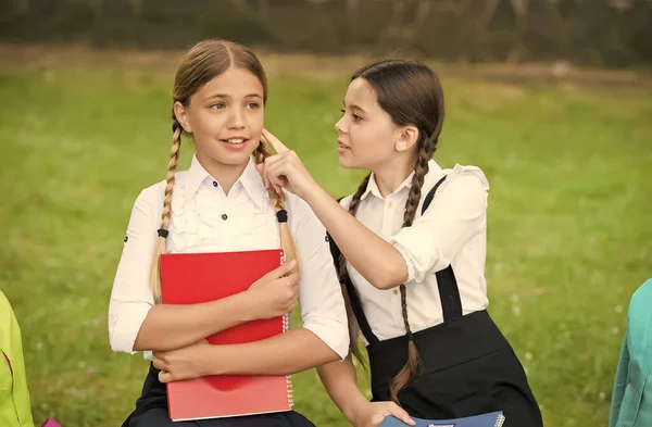 Pequeño niño en uniforme escolar tacto piel de compañero de clase niña sentado en el banco del parque, cuidado de la piel — Foto de Stock