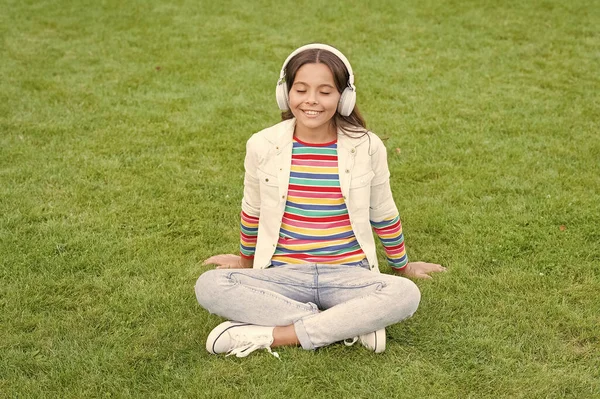 别打扰我了在户外放松的同时听音乐。小女孩喜欢绿色的草地音乐.快乐的时光。儿童耳机听音乐。很酷的女孩耳机听音乐。教育播客 — 图库照片