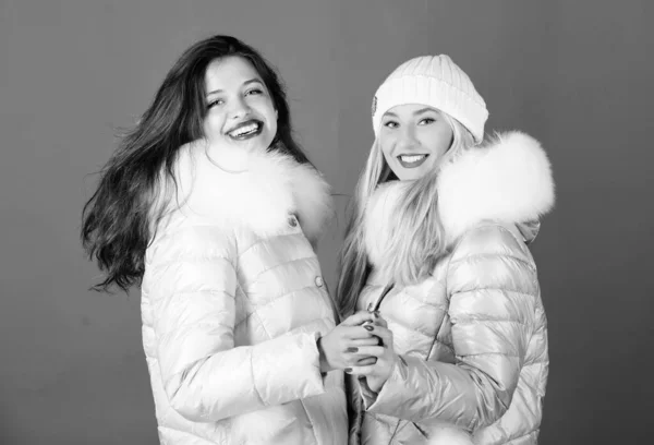 Módní přátelé. Zimní oblečení. Ženy nosí sako s chlupatou kapucí. Dívky usmívající se make-up tváře nosí zimní bundy modré pozadí. Zimní sezóna. Měkká srst. Pro ty, kteří chtějí zůstat moderní — Stock fotografie