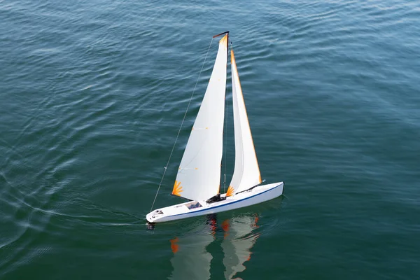 夏休みだ。帆の自由。1機のヨットが海上に出航します。海面におもちゃのボートをセーリング. — ストック写真