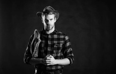 Lasso, rodeo yarışmaları kullanırdı. Kementle bağlanabilir ya da paketlenebilir. Acımasız ve kendinden emin. Batı hayatı. Erkek traşsız kovboy siyah arka planı. Şapka tutan adam. Amerikan kovboyunun kementi.