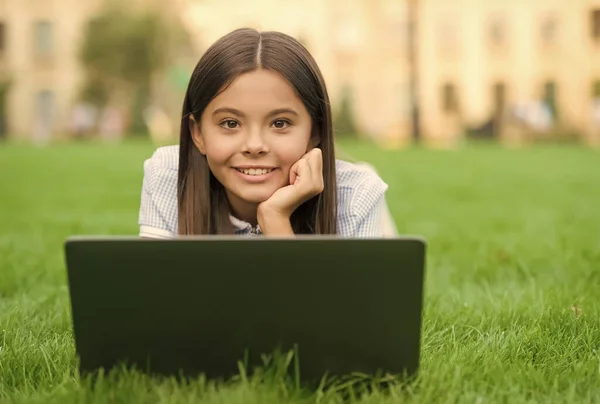 Niño feliz trabajando en el ordenador portátil. educación en línea. de vuelta a la escuela. adolescente uso de la computadora en la hierba verde en el parque. niño con cuaderno. nueva tecnología en la vida moderna. Estudia. Compras online — Foto de Stock