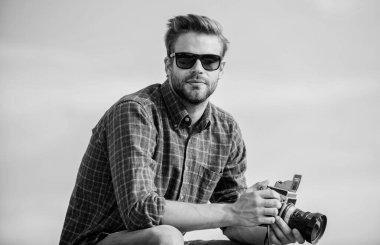 Elle ayarlar. Fotomuhabir konsepti. Gezgin blogcu. Gazeteci fotoğraf çekiyor. Adam açık havada gökyüzü arka planında. Antika ekipmanlar. Blogger video blogu çekiyor. Yakışıklı blogcu adam gezgin geçmişe dönük kamera