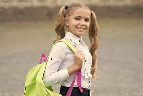 Mądry jest świetny... z powrotem do szkoły. Dziecko w mundurze nosi torbę szkolną. koncepcja edukacji. rozwój dzieciństwa. szczęśliwa dziewczyna ma ładny uśmiech. szczęśliwy przedszkola dziewczyna z plecakiem w podwórku szkolnym — Zdjęcie stockowe