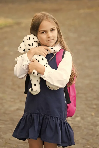 愛らしい小さな子供の抱きしめかわいいおもちゃの犬は、屋外で学校の制服のバックパックを着て、放課後 — ストック写真