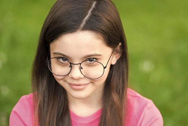 Kislány visel vintage felni szemüveg zöld gyep háttér, félénk baba koncepció — Stock Fotó