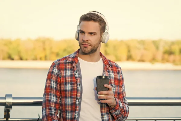 Ώρα για διάλειμμα. Ο άνθρωπος με τα ακουστικά ακούει το τραγούδι. στυλ μουσικής. μαθαίνοντας πίνοντας καφέ. ποιότητα του ήχου. Καλημέρα ποτό. αξύριστος τύπος με φλιτζάνι καφέ. αρσενικό casual μόδα hipster — Φωτογραφία Αρχείου