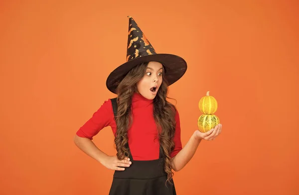 Jack o lantern. happy halloween. surprised kid wear witch hat. child with small pumpkin. teen girl has long curly hair and wear dress for party celebration. autumn season holiday. childhood leisure — Stock Photo, Image