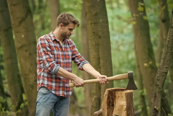 Hombre musculoso con camisa a cuadros con hacha en el bosque, actividad masculina —  Fotos de Stock