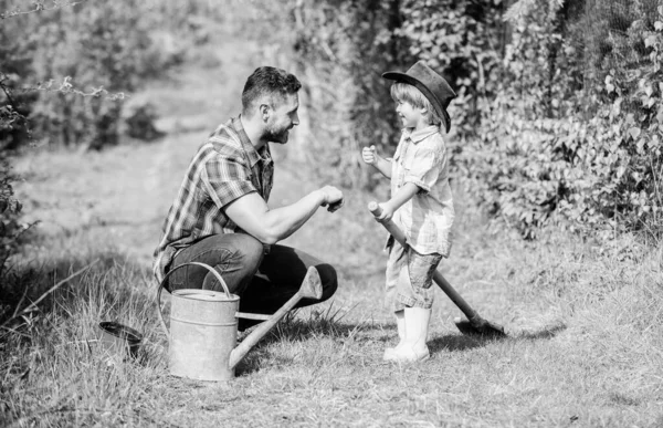 Vader en zoon met cowboyhoed op de ranch. Eco boerderij. kleine jongen kind te helpen vader in de landbouw. gieter, pot en schep. Tuinbenodigdheden. Gelukkige dag op aarde. Familie boomverzorgers. Laten we alles controleren. — Stockfoto