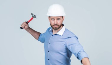 İş patronu sakallı ve kıllı. Sert şapka giyer. Çekiç tutar, işçi günü.