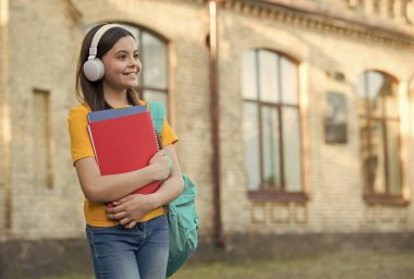 Mutlu ilkokul çocuğu modern kulaklık takıyor yabancı dil kursları dinliyor, fotokopi çekiyor.