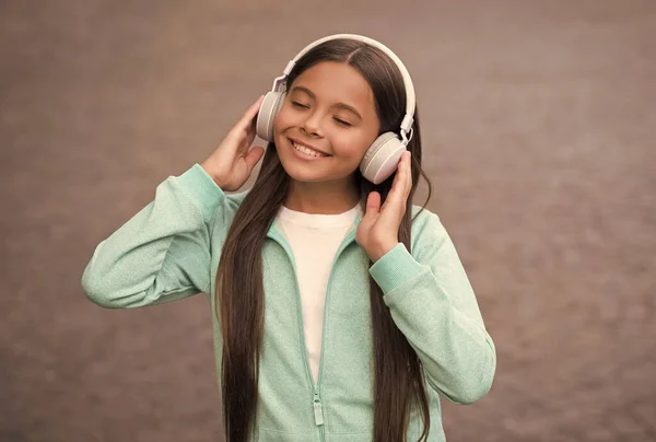 Wesoła dziewczyna nosić słuchawki z piosenką muzyki outdoor korzystających melodii, szkoła edukacji online — Zdjęcie stockowe