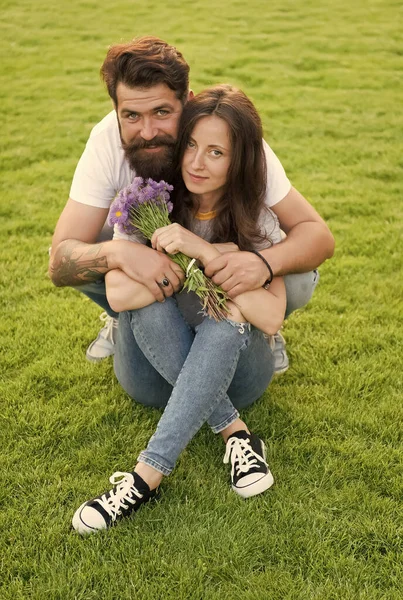 Šťastný den žen. Vousatý muž dává květiny sexy ženě. Šťastný pár zamilovaný do zelené trávy. Slavíme dámský den. Květinářství. Mezinárodní dámská dovolená. Den žen 8. března — Stock fotografie