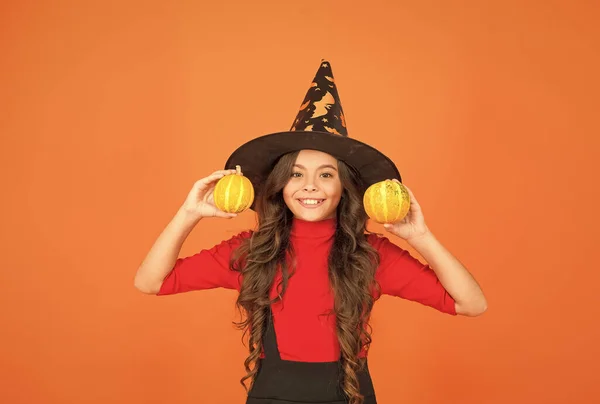 Criança feliz no traje de chapéu de bruxa para halloween com pequena abóbora amarela, comida de halloween — Fotografia de Stock